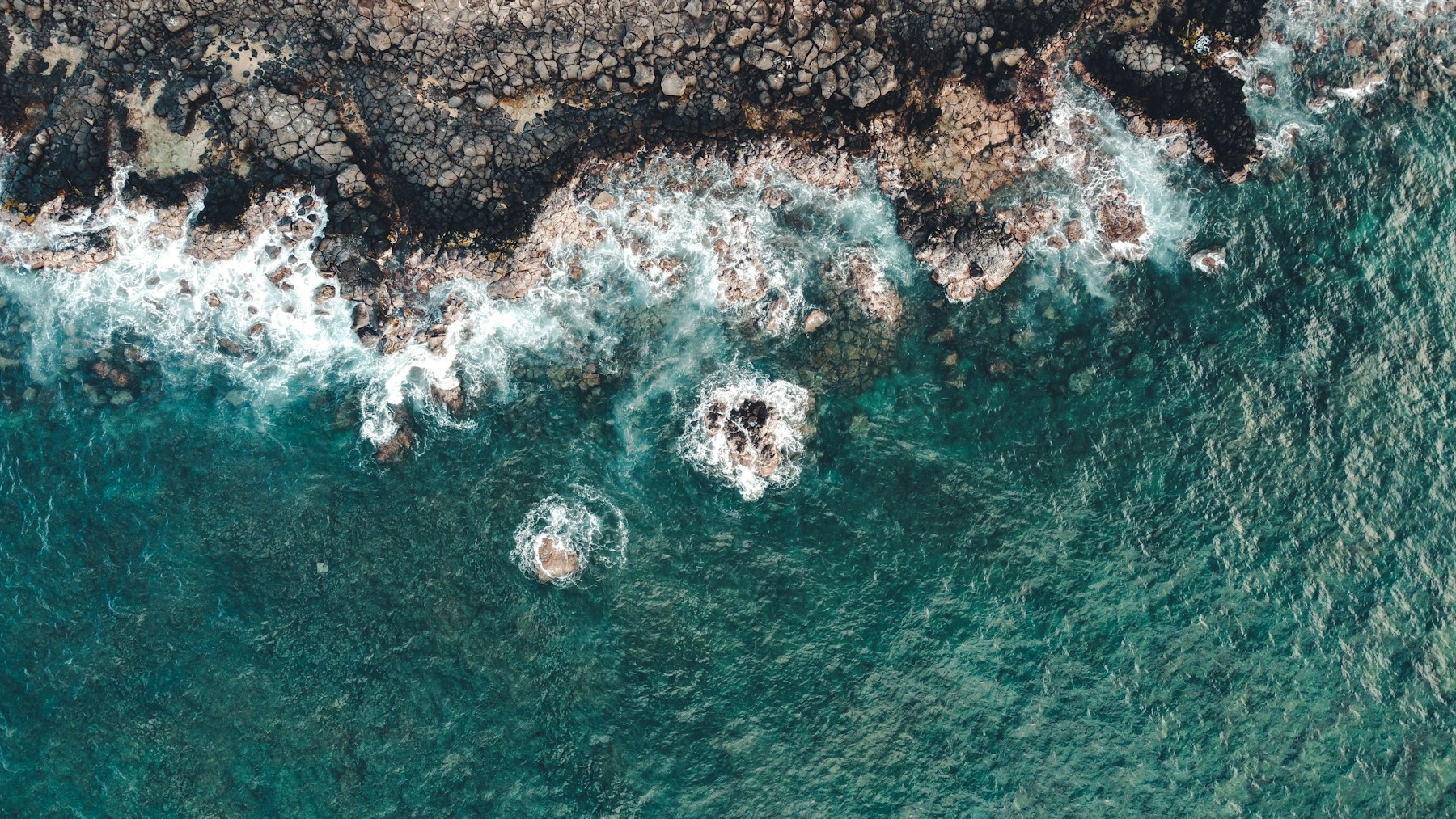 Turquoise waves breaking over a rocky coastline