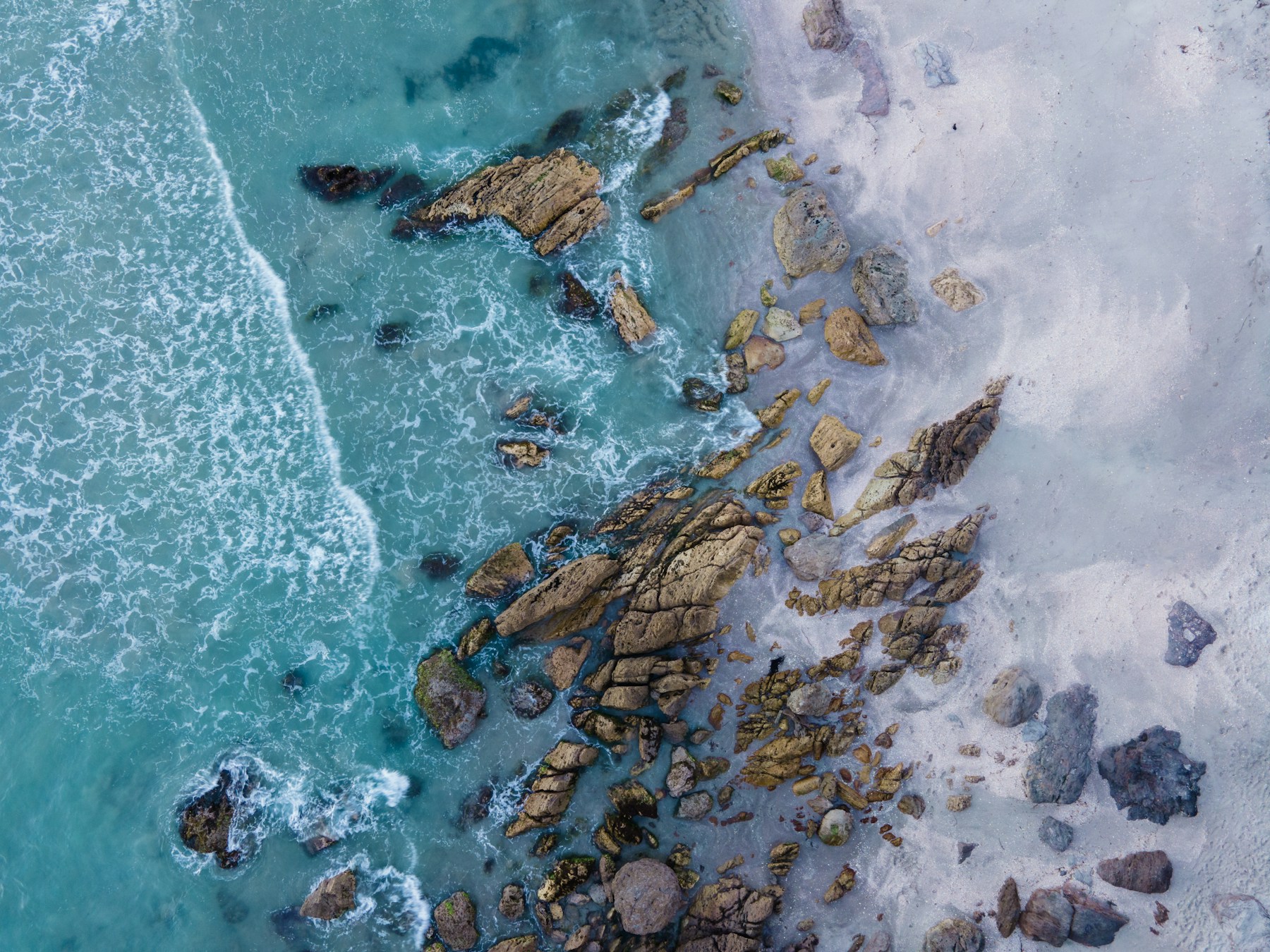 Aerial view of clear water and scattered coastal rocks