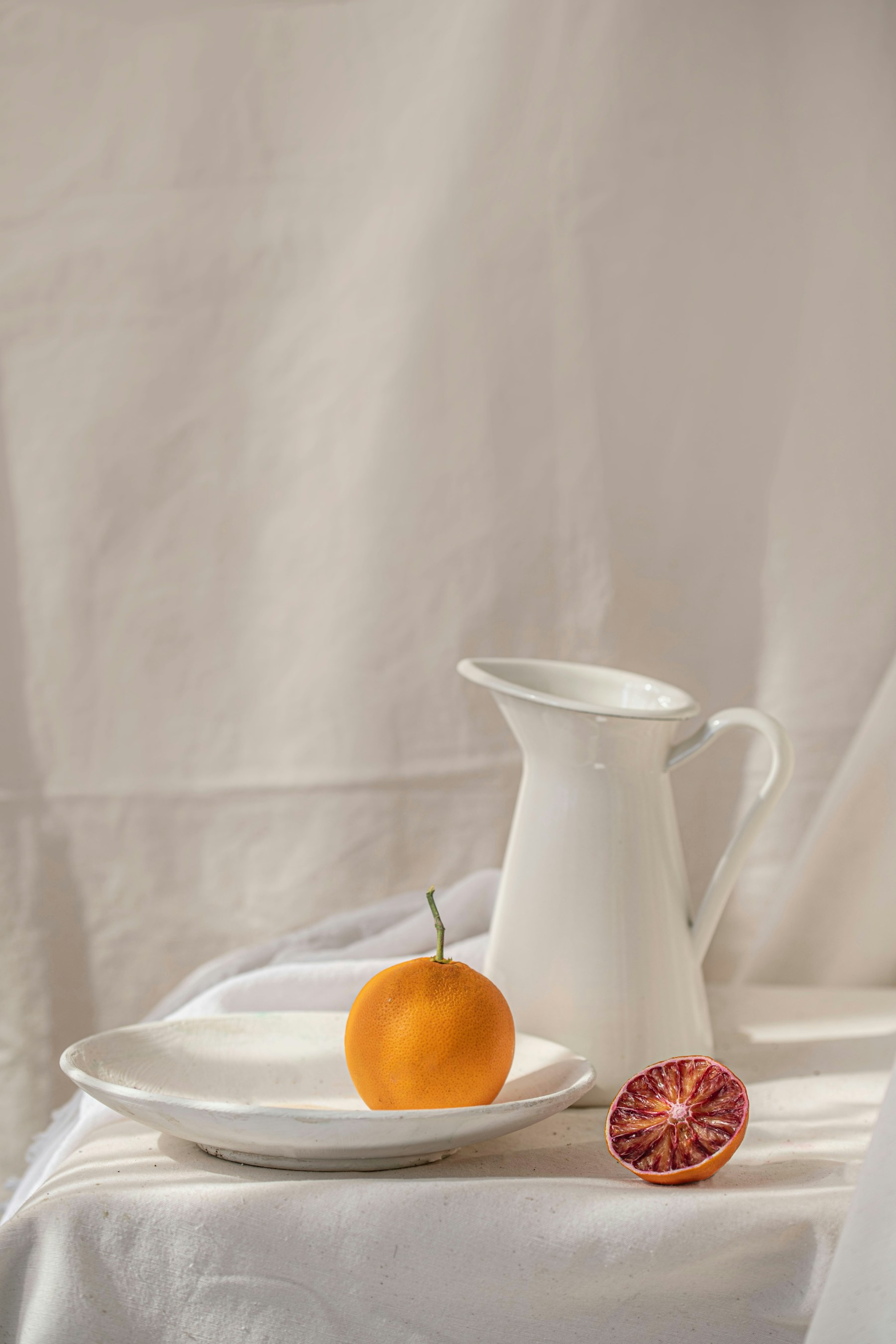 Citrus fruit and white ceramics arranged on softly folded linen